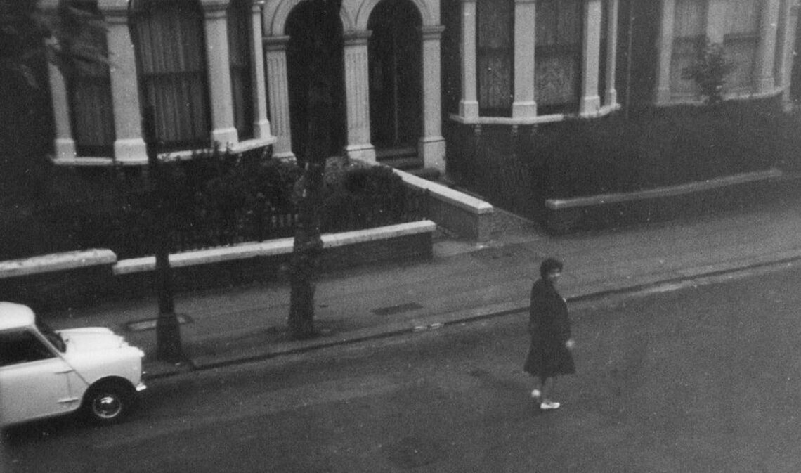 grayscale photo of woman walking on street