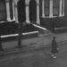 grayscale photo of woman walking on street