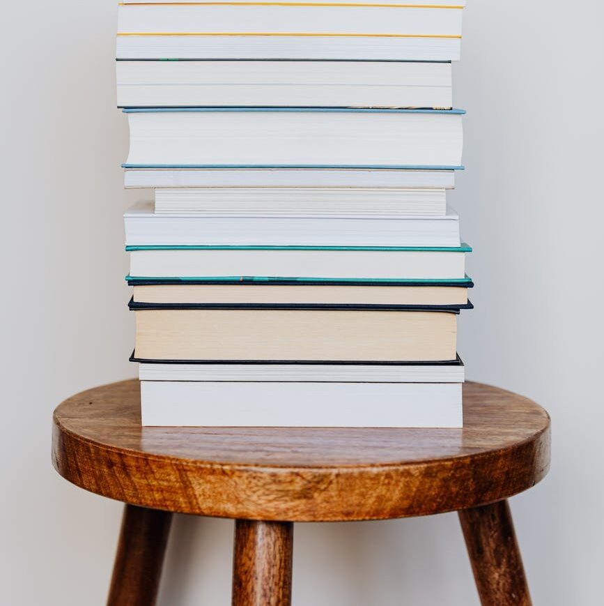 big pile of books on wooden stool